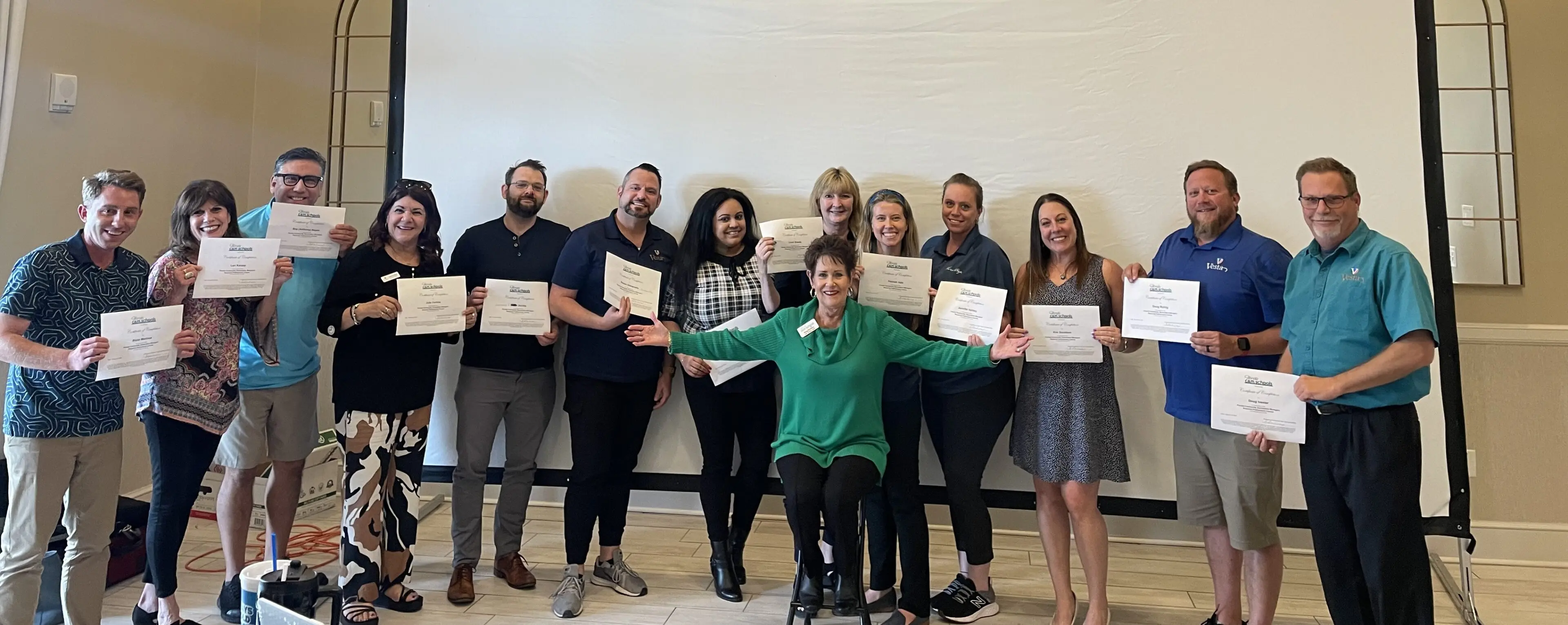 A group of people holding certificates in front of a wall.