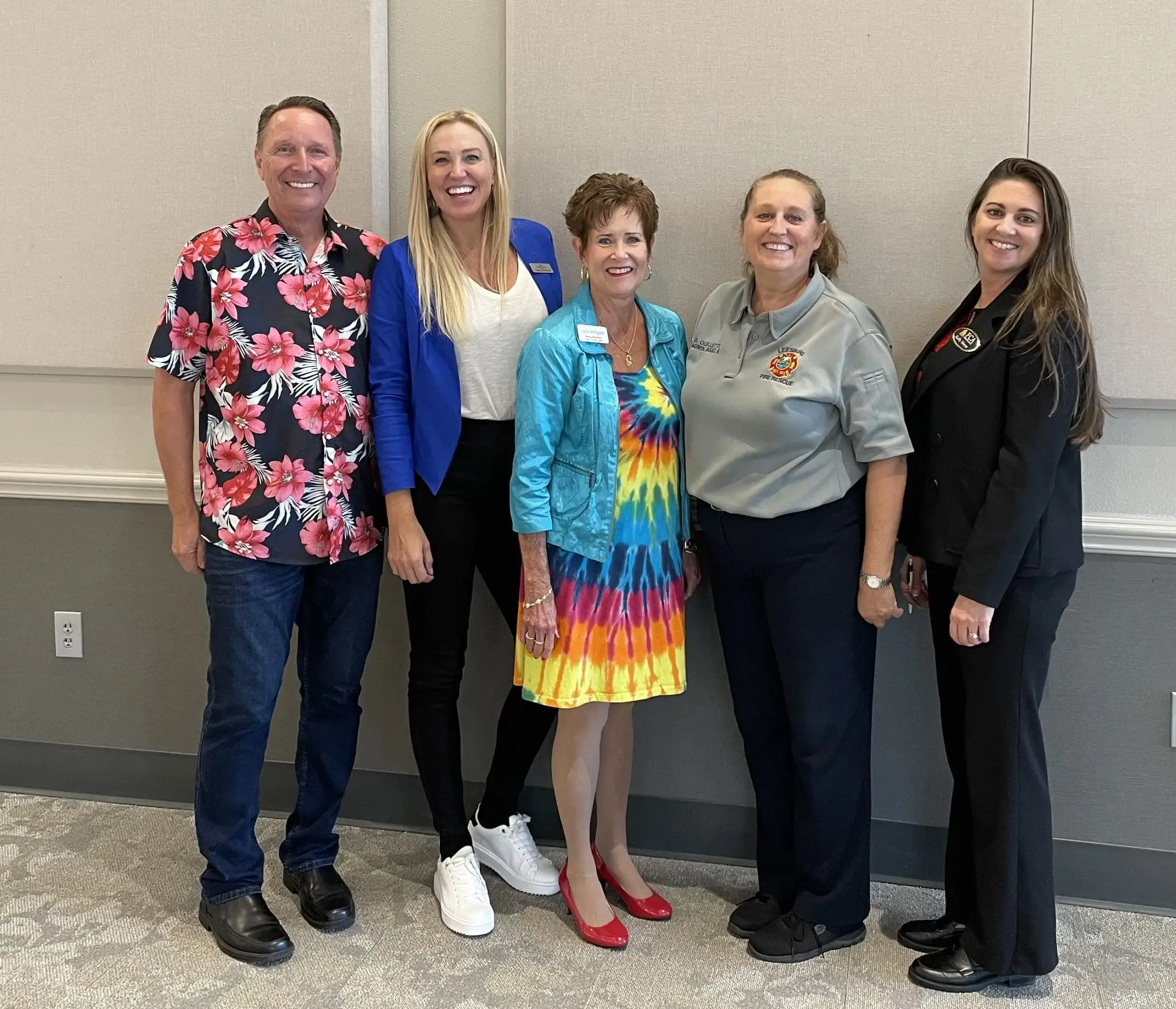 Five smiling adults posing indoors