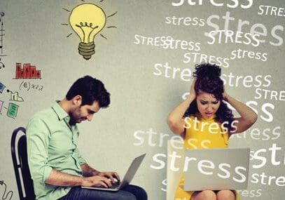 A man and woman sitting on the ground with laptops.